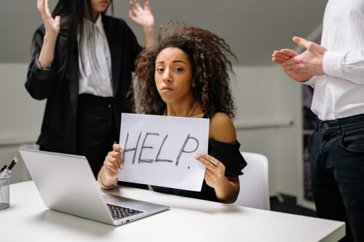 Personne stressée, tendant un panneau "Help"